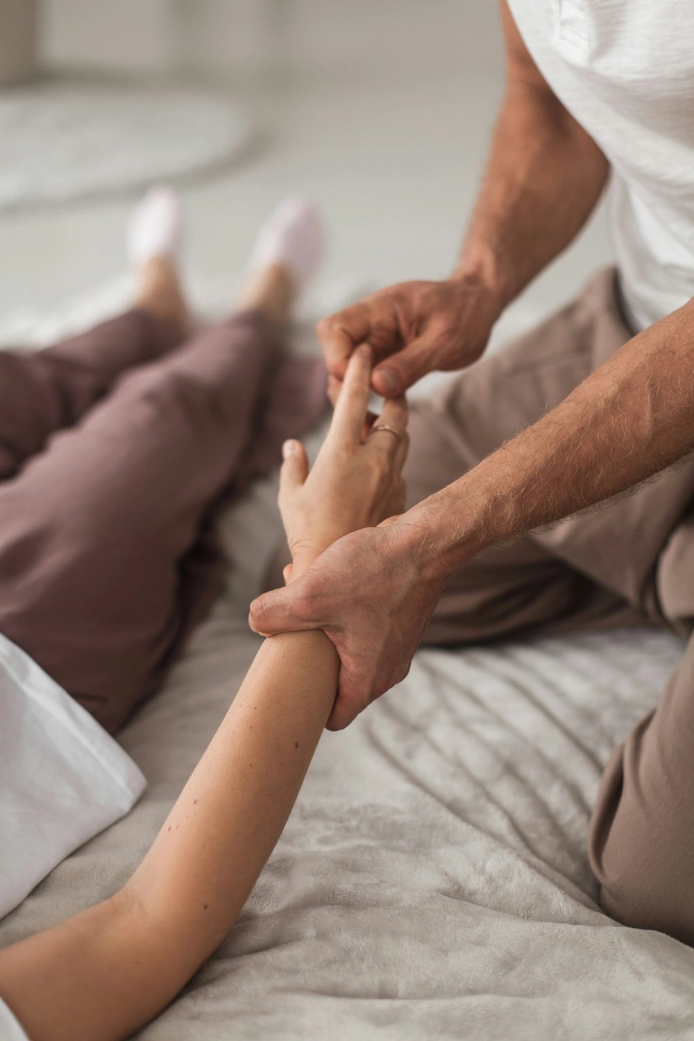 Physiotherapie Balance - Physiotherapie - Ein Therapeut massiert die Hand und den Unterarm einer Person.