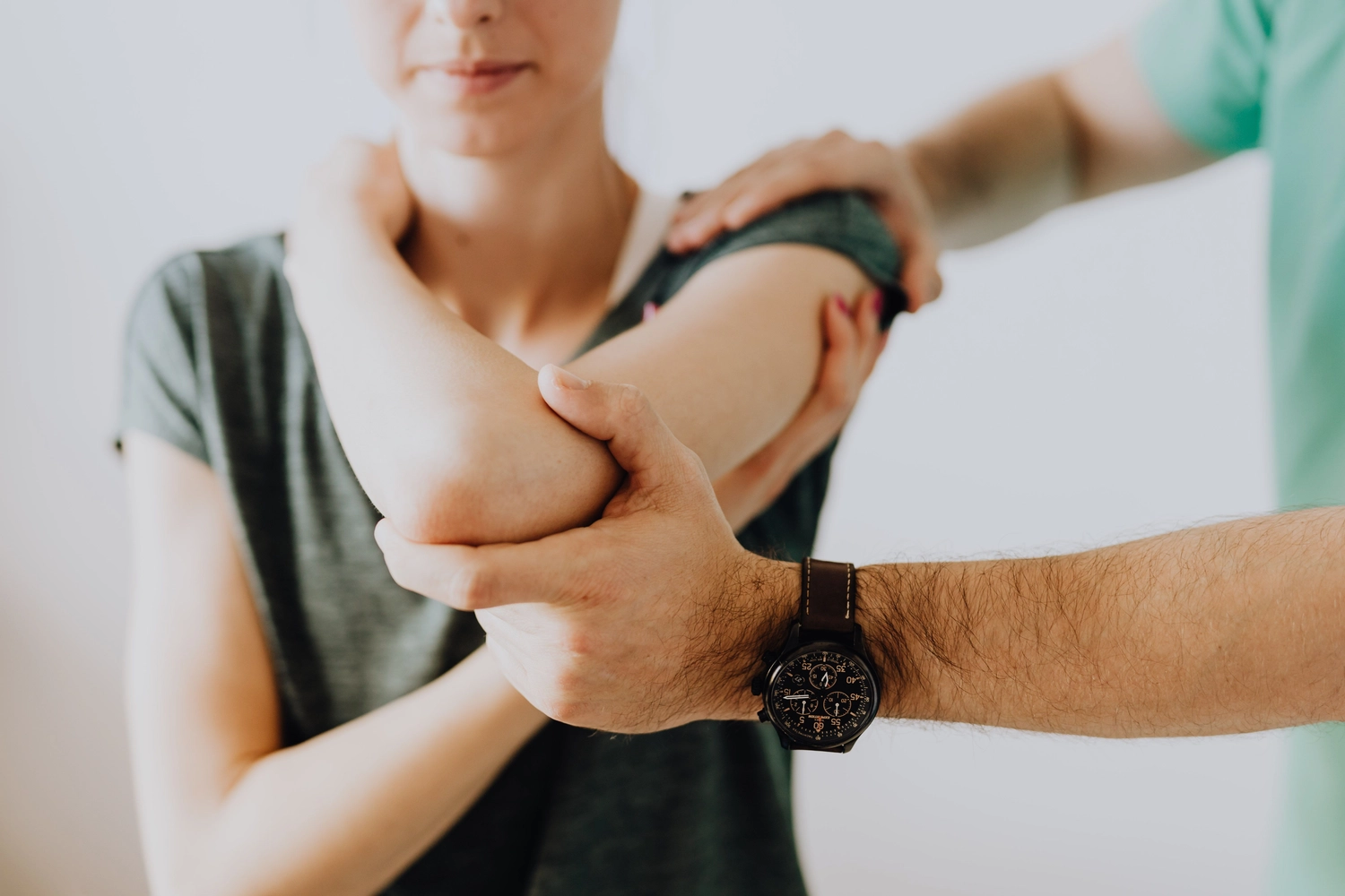 Physiotherapie Balance - Physiotherapie - In einem hellen Studio leitet eine Physiotherapeutin eine sitzende Frau durch eine Dehnübung zur Mobilisierung der Schulter.