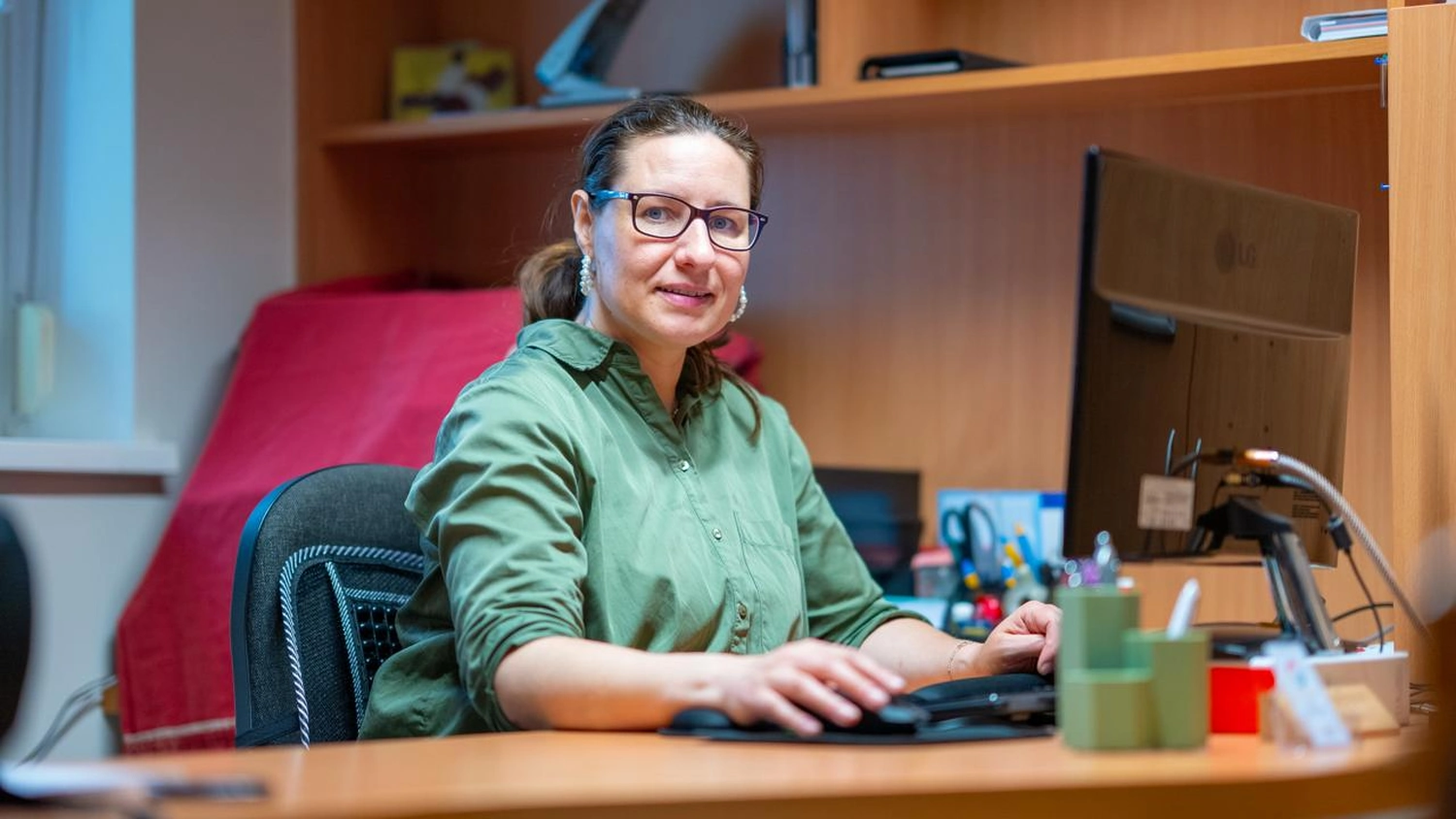 Physiotherapie Balance - Physiotherapie - Veronika Nickel mit Brille sitzt an einem Büroschreibtisch und benutzt einen Computer.